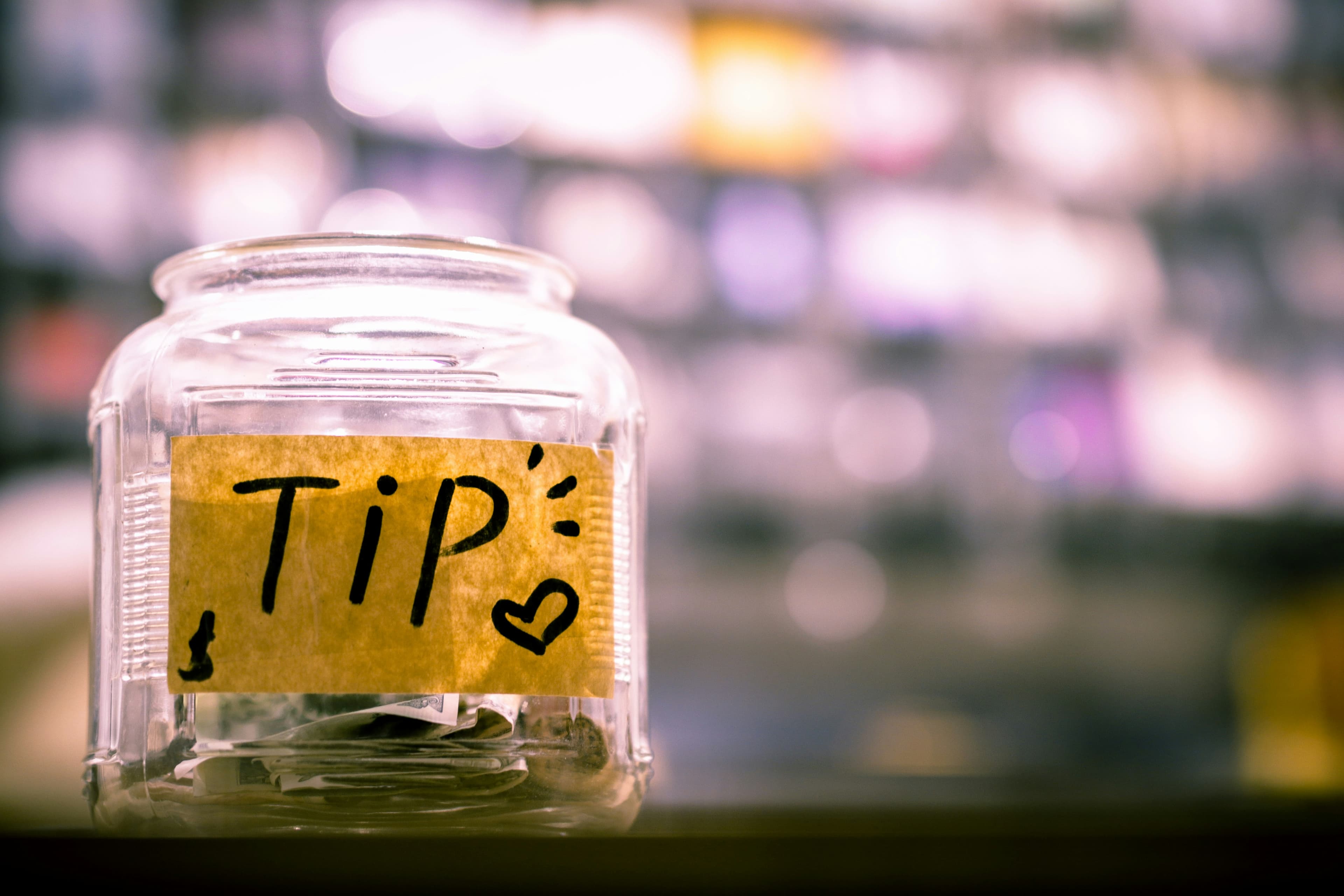 Bocal en verre de contributions libres étiqueté Tip sur un comptoir